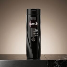 Sunsilk Black Shine Shampoo 185ml dark bottle on a sleek black marble surface from Chaudhary Superstore