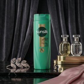 Sunsilk Long & Lustrous Shampoo 360ml green bottle displayed on a luxury dark marble surface with botanical props by Chaudhary Superstore